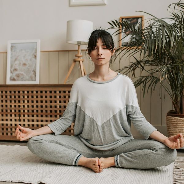 Woman meditating peacefully in a natural setting with soft light.